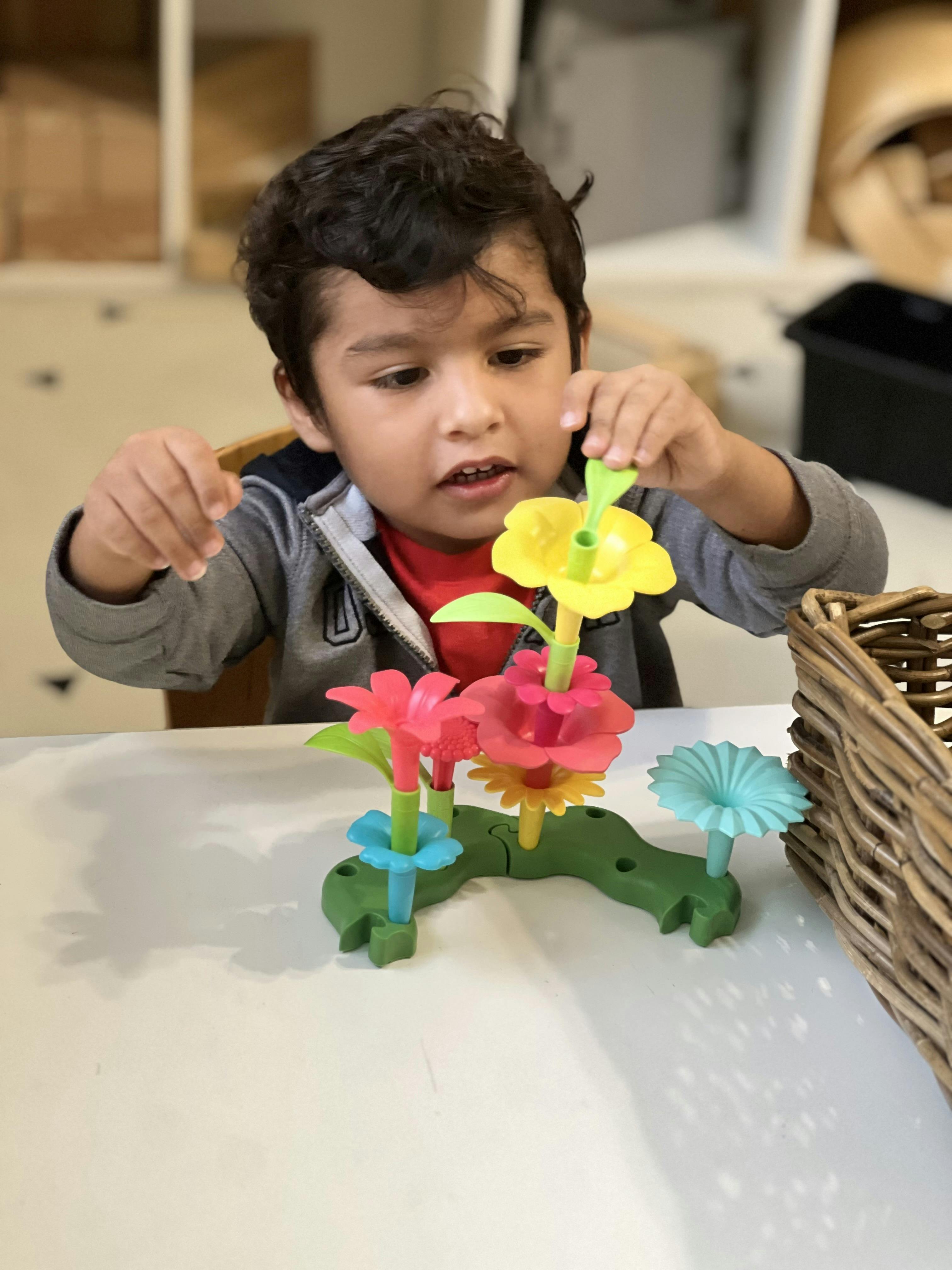Child building a toy flower garden on a table