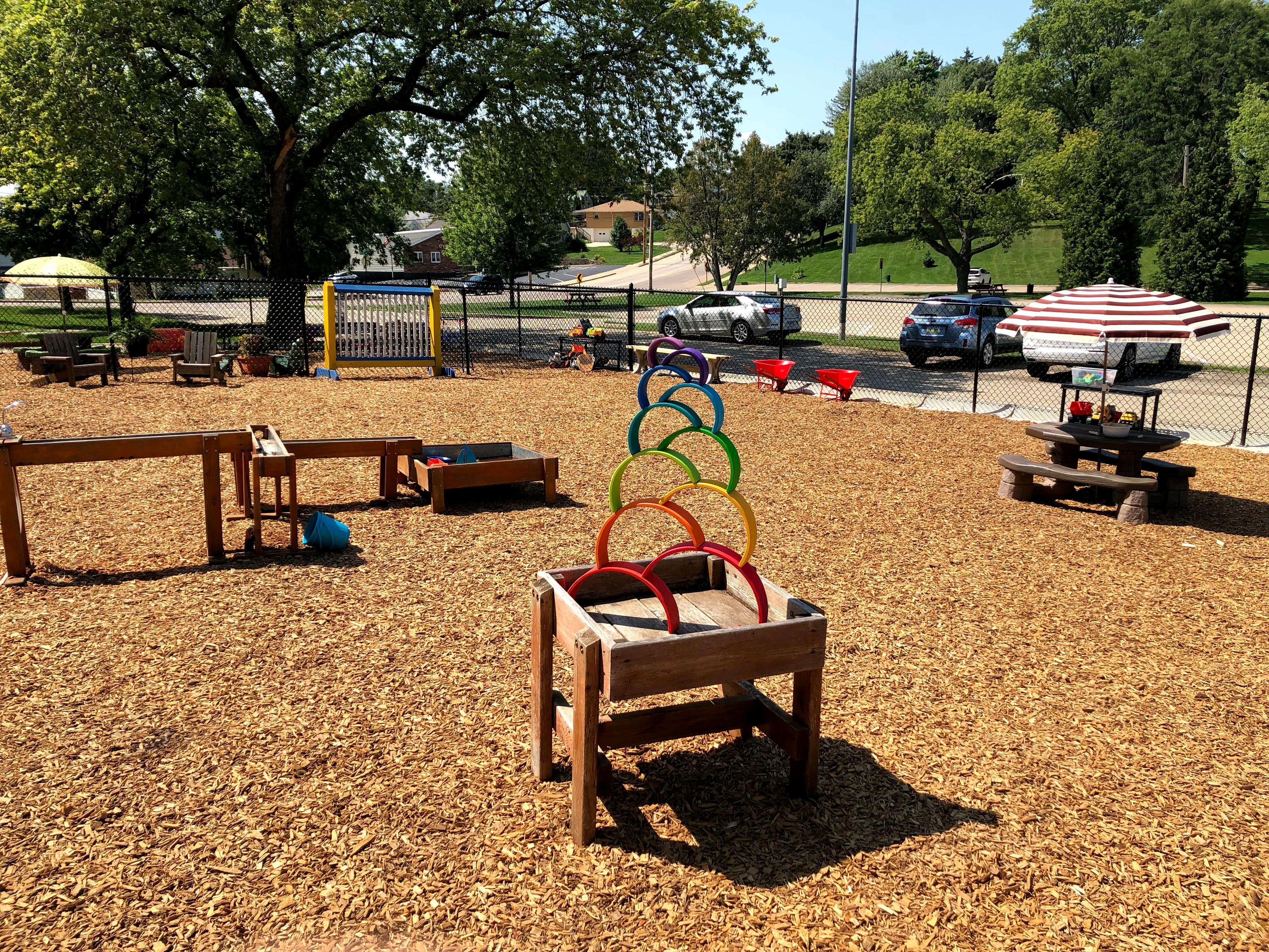 Outdoor playground with wood chips, play structures, and picnic tables