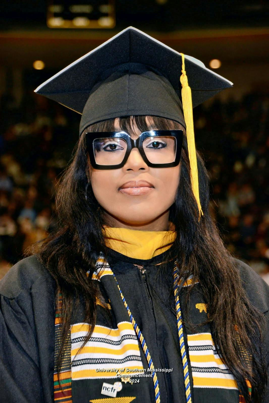 Person in a graduation cap and gown with glasses