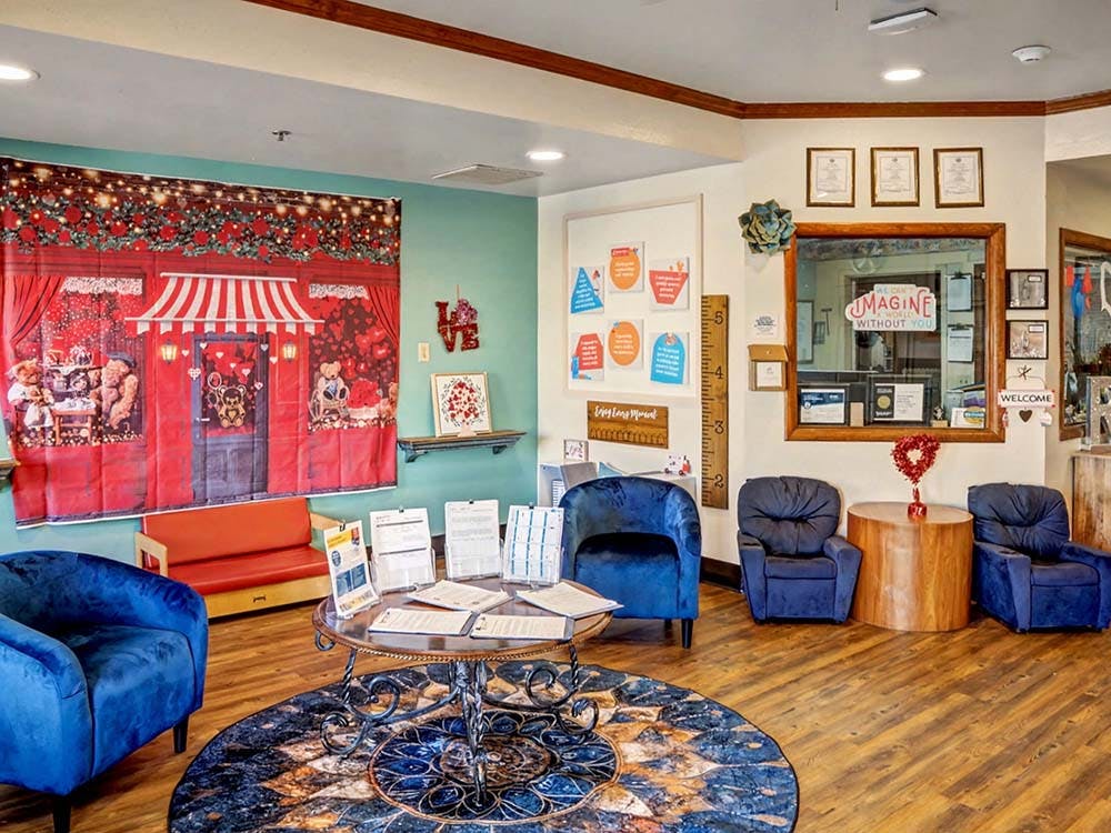 Lobby with a decorative backdrop, a round table with papers, and blue chairs