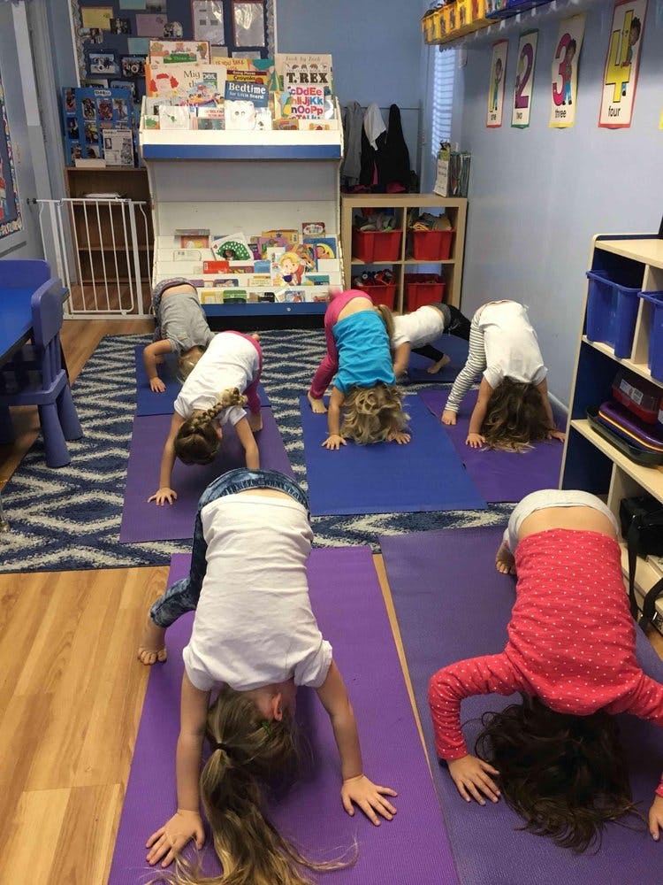 Children doing downward dog yoga pose in a classroom