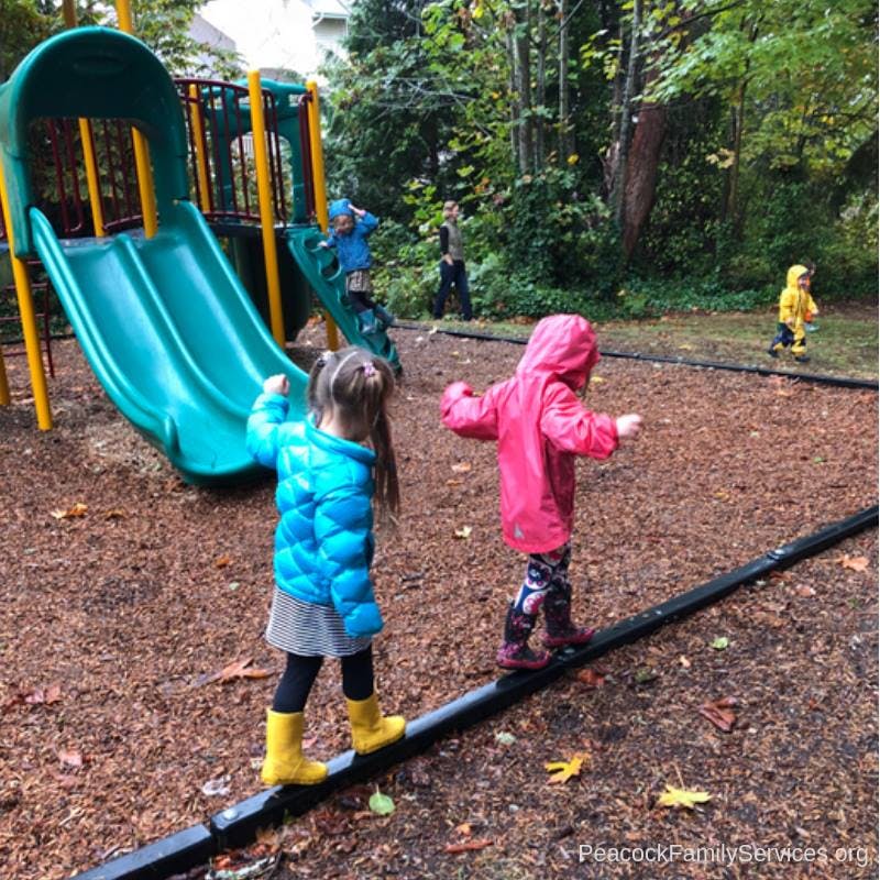 Children playing on a playground with slides and a balance beam
