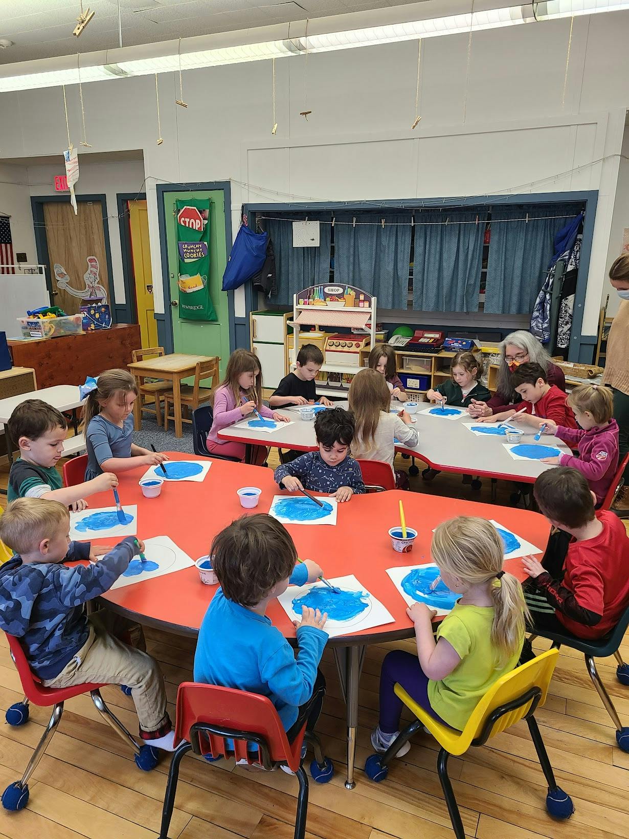 Children painting at tables in a classroom