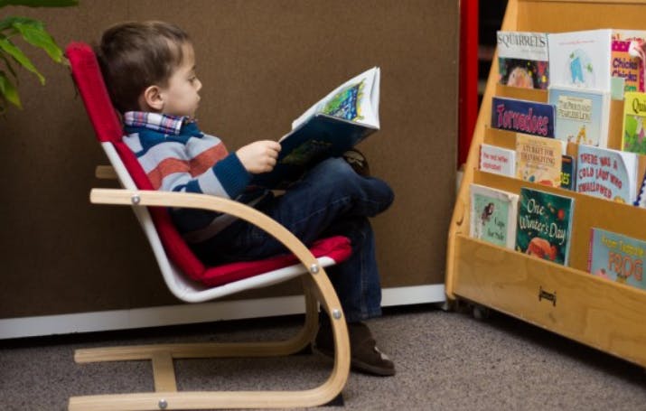 Child sitting in a chair reading a book