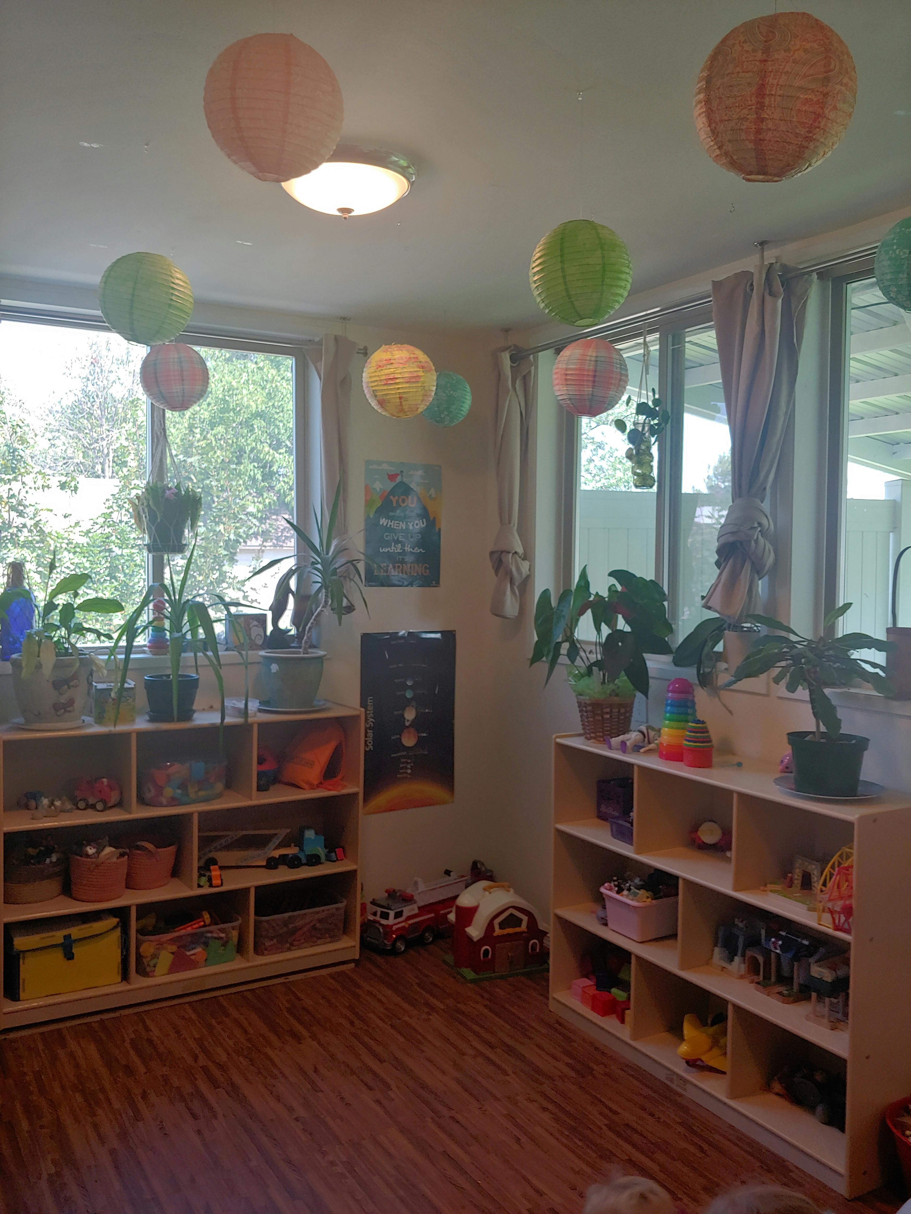 Classroom with paper lanterns, plants, and shelves with toys