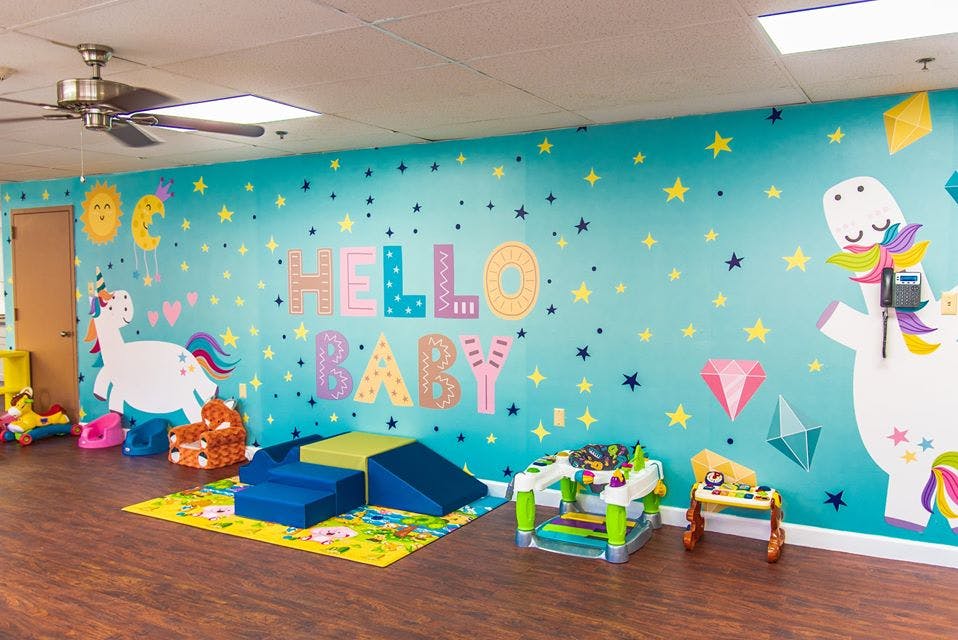 Playroom with "Hello Baby" on wall, soft play equipment, and toys