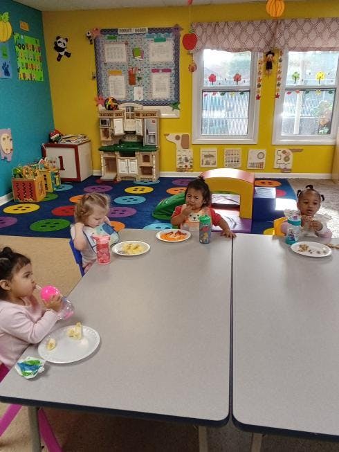 Four children eating at tables in a colorful room
