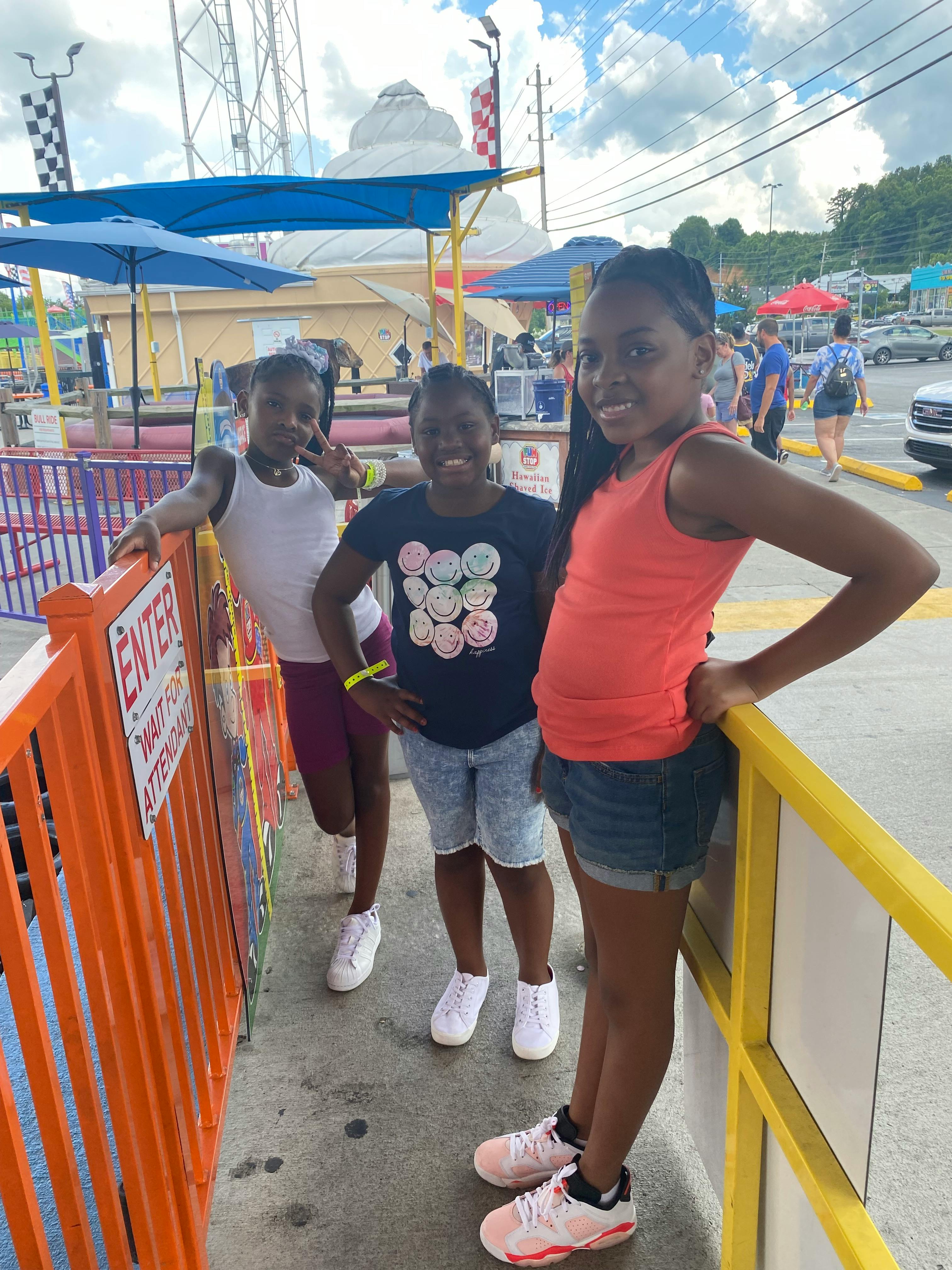 Three children standing by a fence with an "ENTER" sign