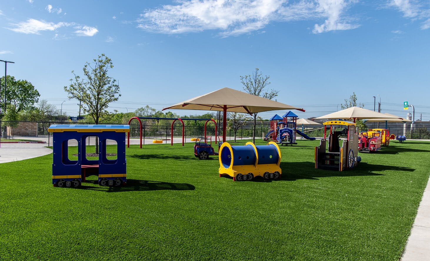 Playground with train-shaped play structures on green turf
