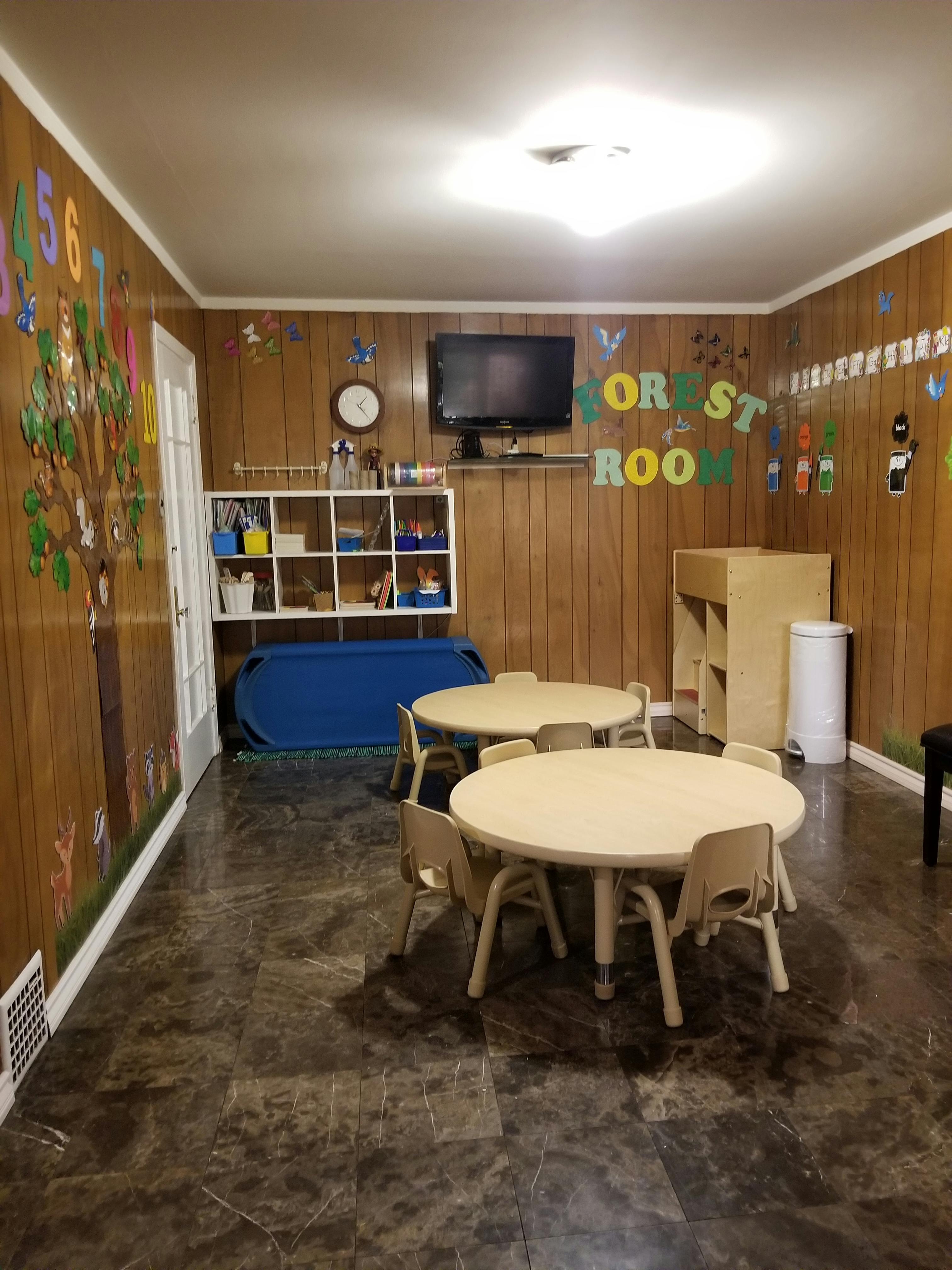 Classroom with small tables and chairs, storage shelves, and a television