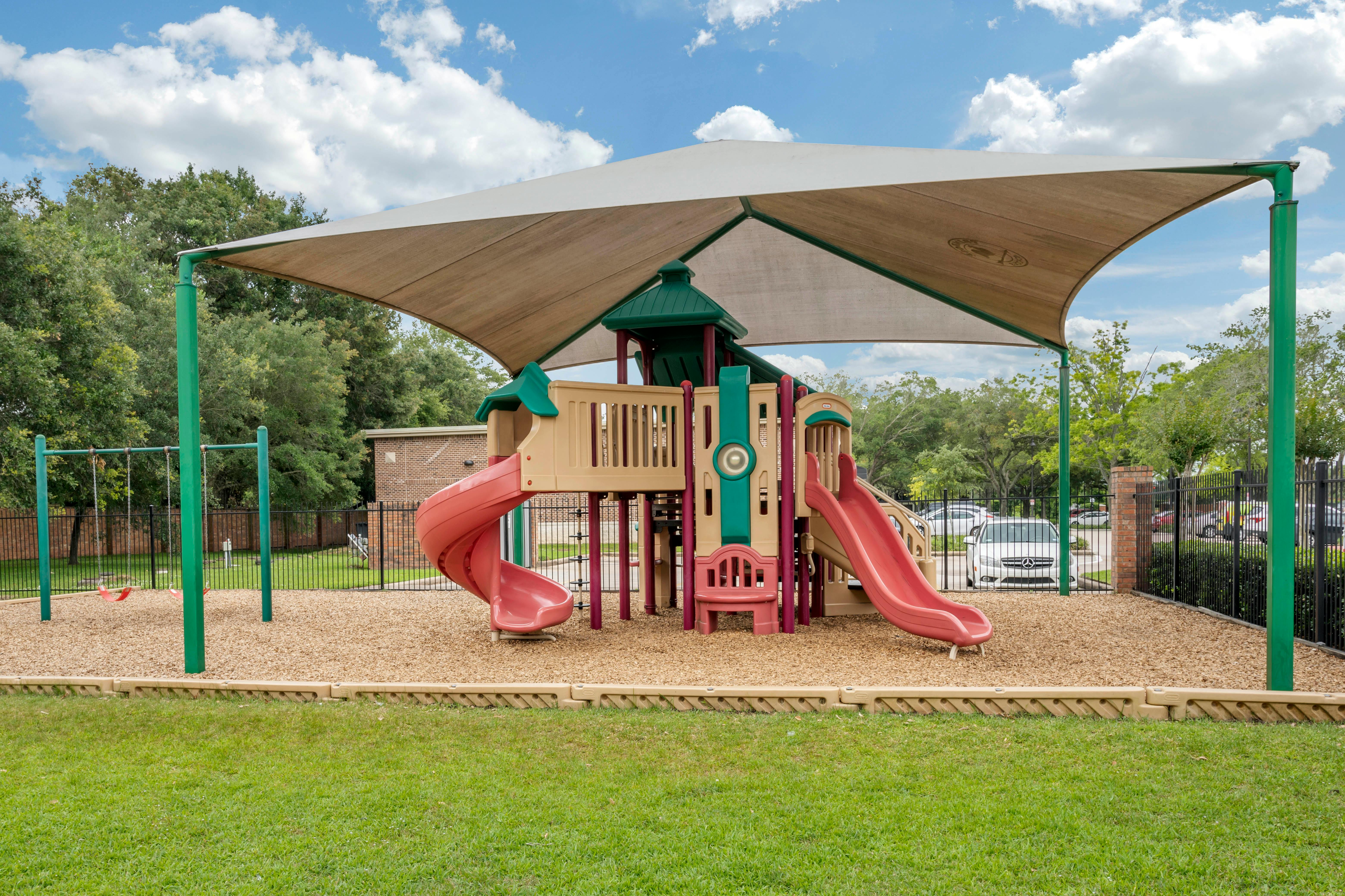 A colorful playground with slides and swings under a large canopy