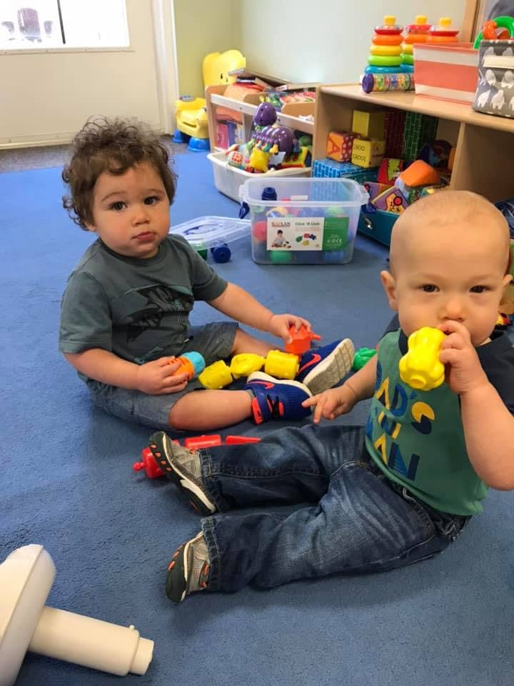 Two children playing with toys on a blue floor