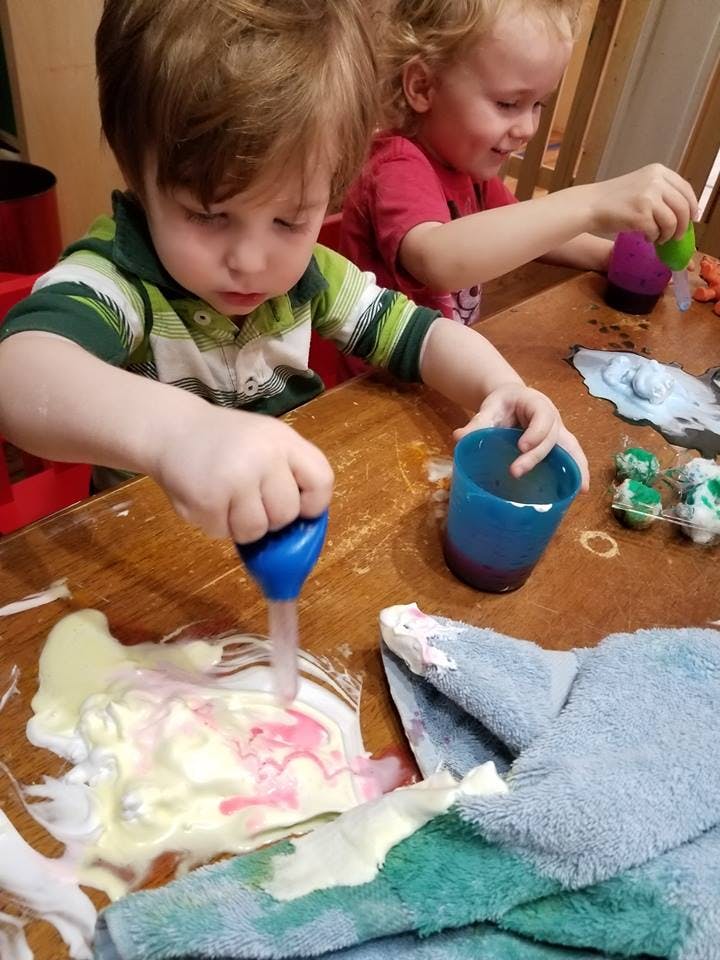 Child using a dropper to mix colors on a table