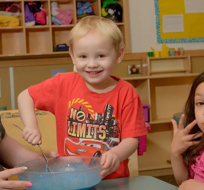 Child stirring a bowl of blue liquid