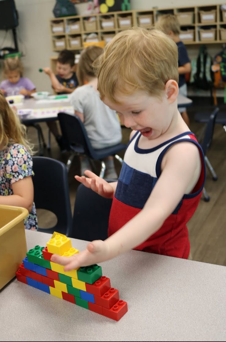 Child playing with colorful building blocks in a classroom