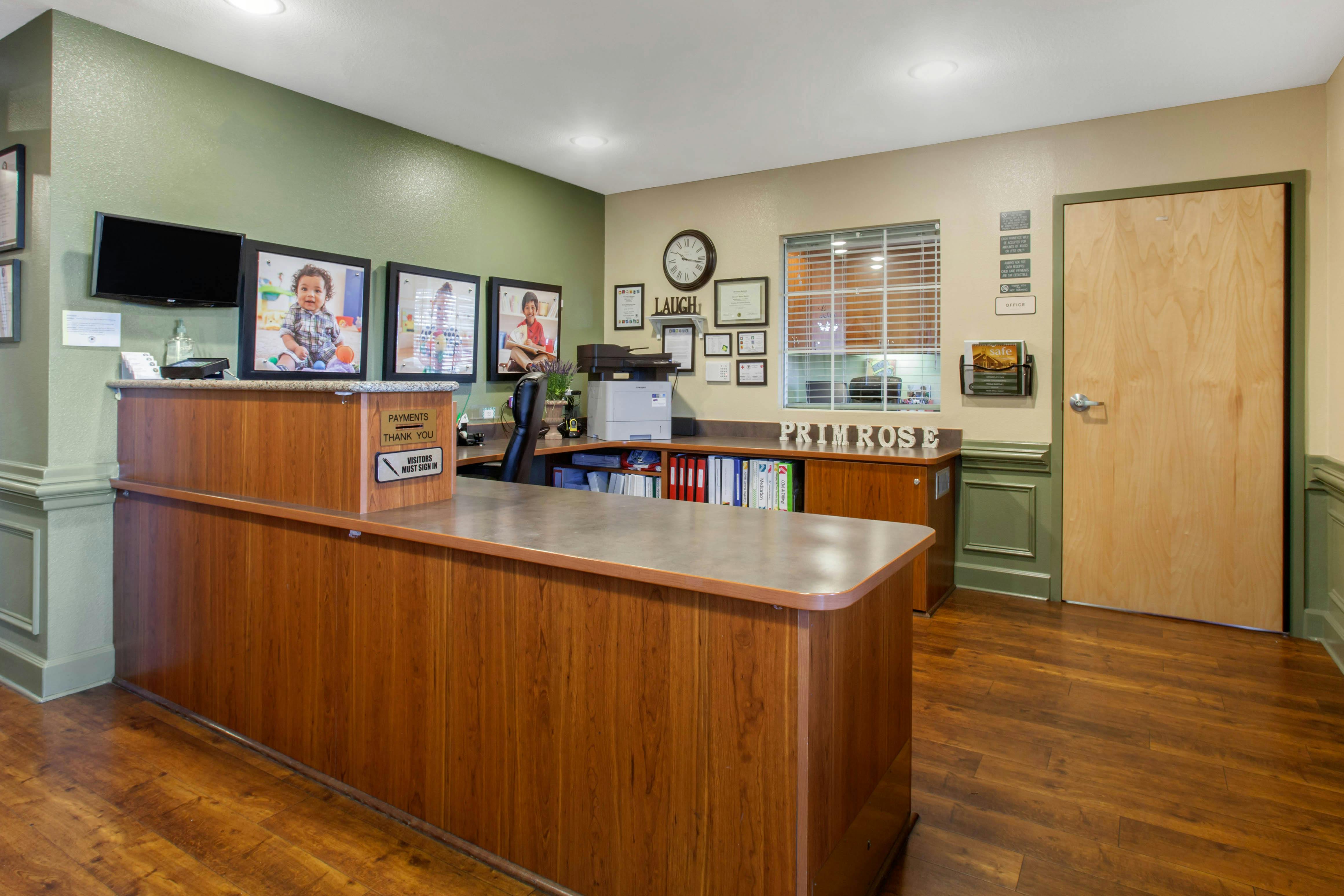 Reception desk with photos of children on the wall and a sign that says Primrose