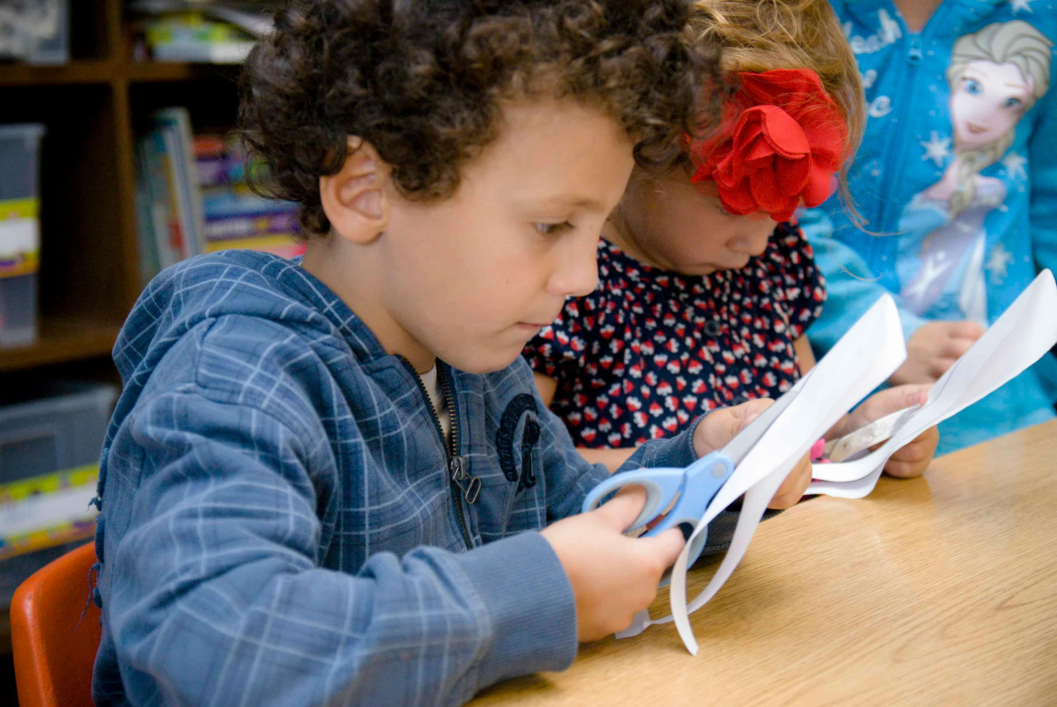 Child cutting paper with scissors in a classroom