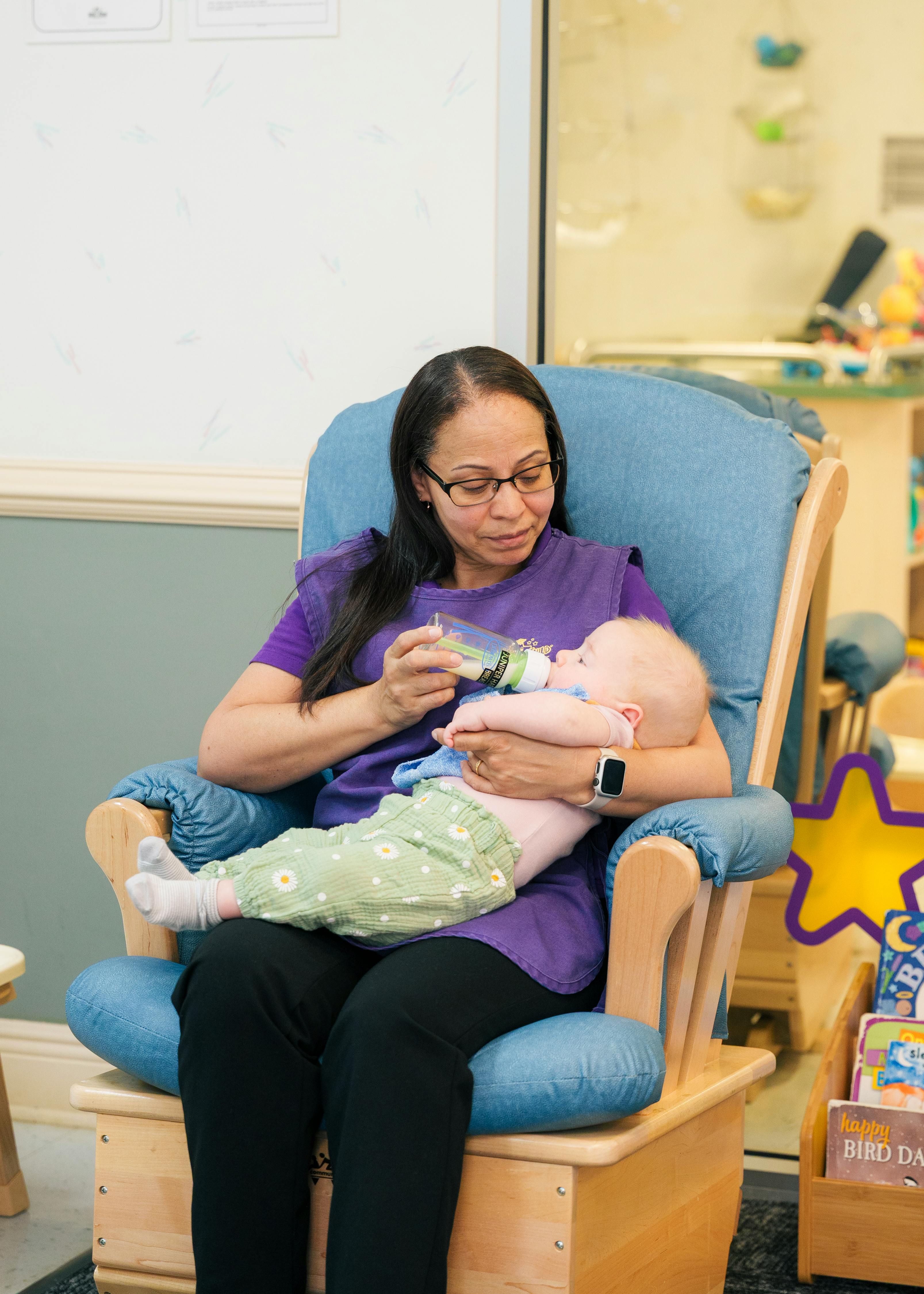 Person in a rocking chair bottle-feeding a child