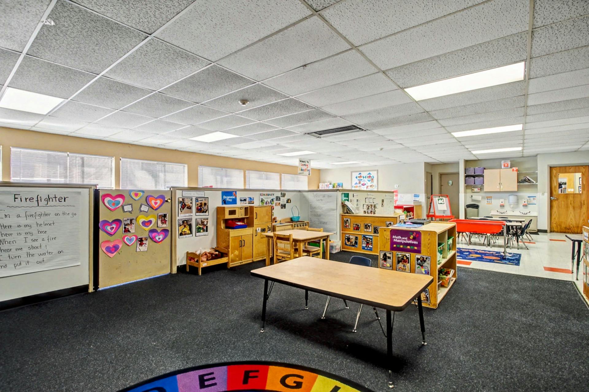 Empty classroom with small tables, chairs, and shelves