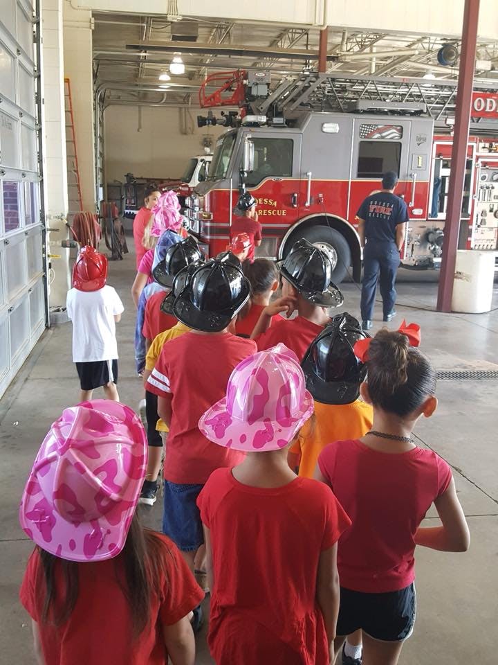 Children wearing fire hats looking at a fire truck in a fire station