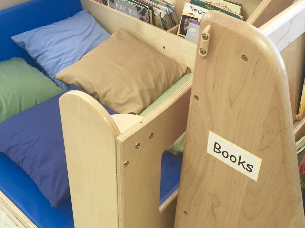 Pillows on a blue bench next to a wooden bookshelf with a "Books" label