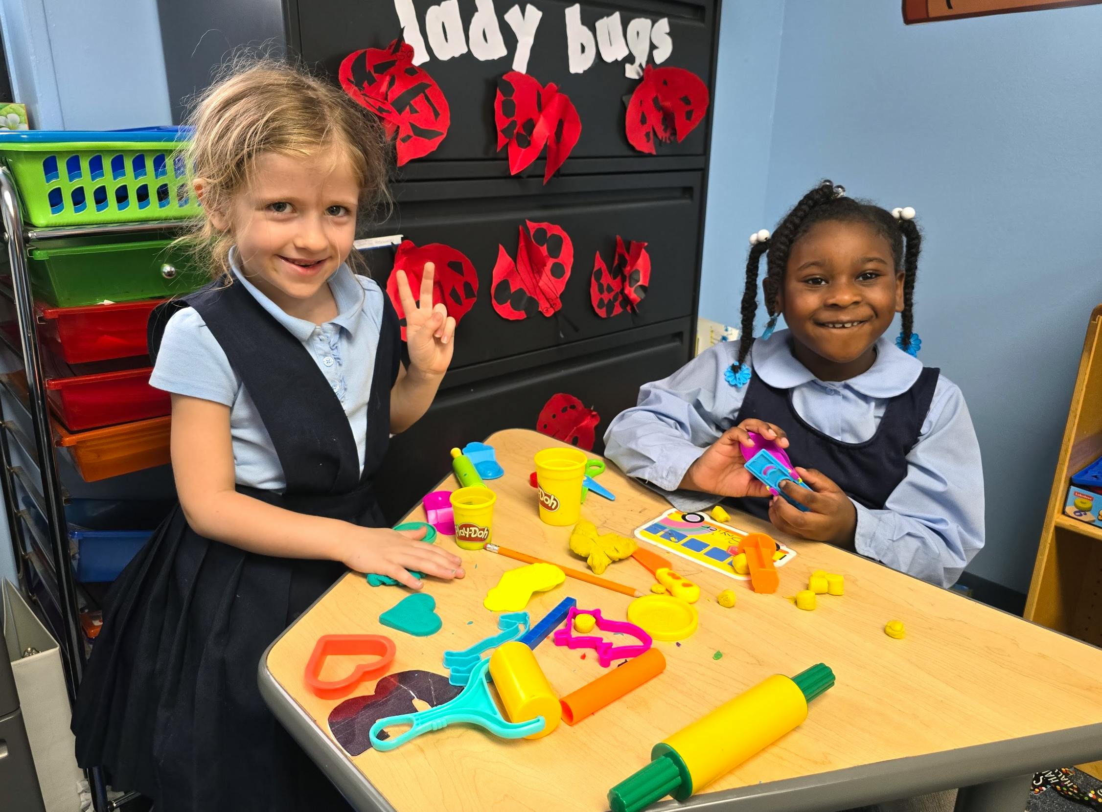 Two children playing with modeling clay at a table in a classroom