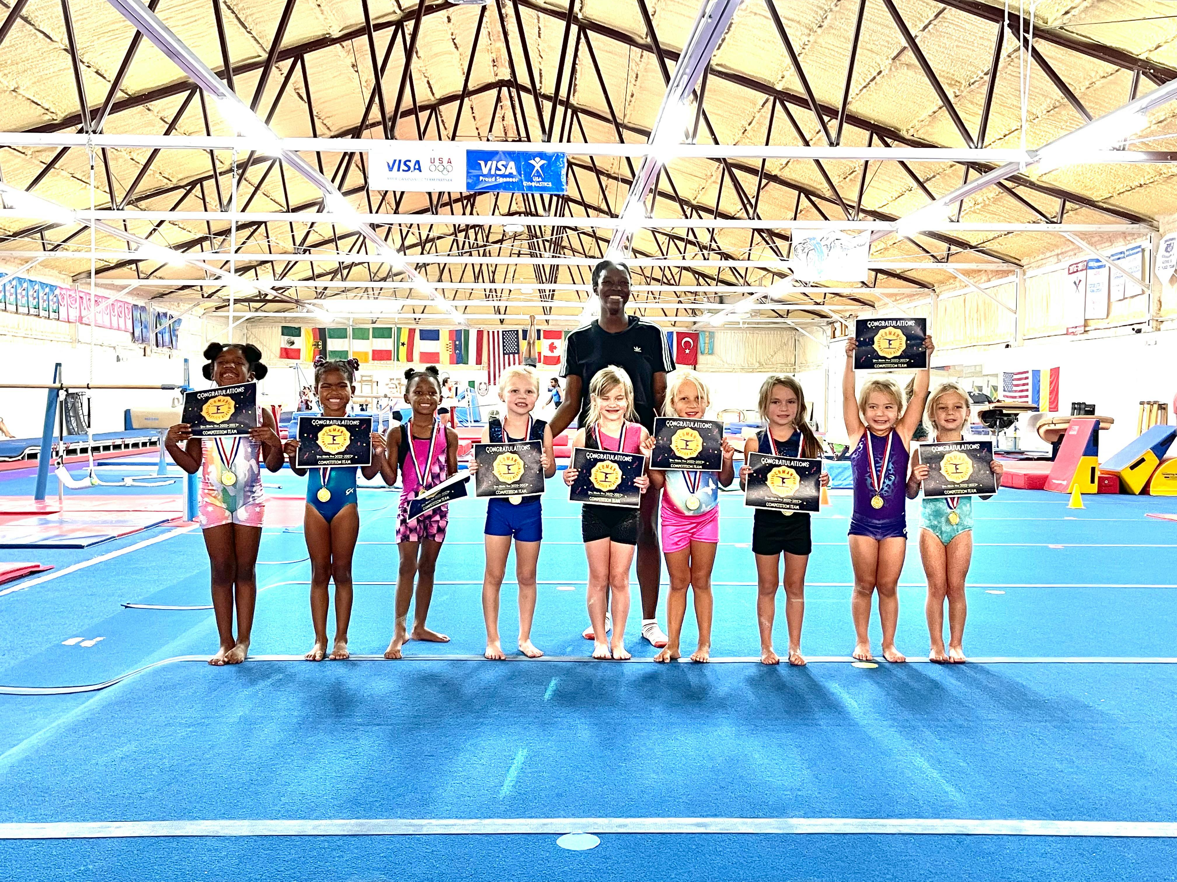 Person and children holding awards in a gymnasium