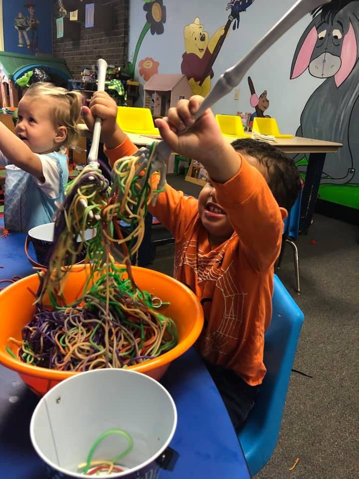 Child playing with colorful string in a classroom