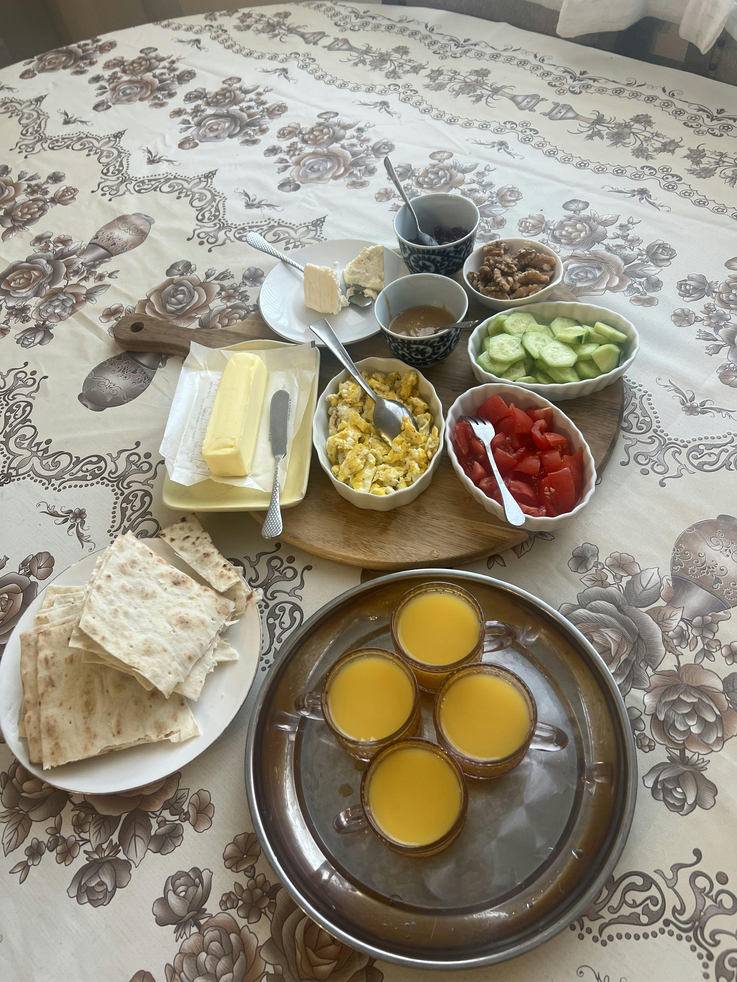 A breakfast spread with eggs, vegetables, cheese, bread, and glasses of juice