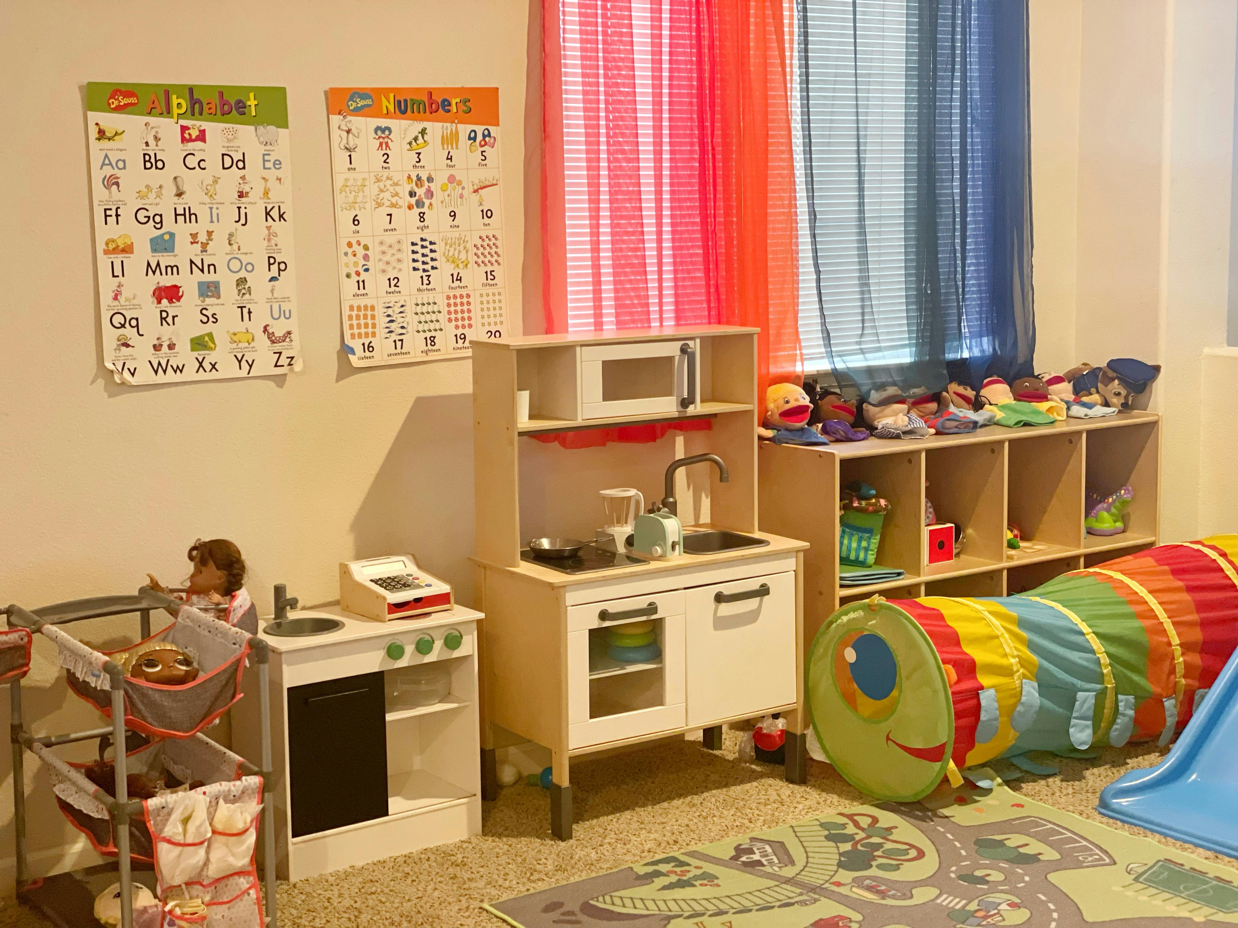 Playroom with toy kitchen, play tunnel, and alphabet charts