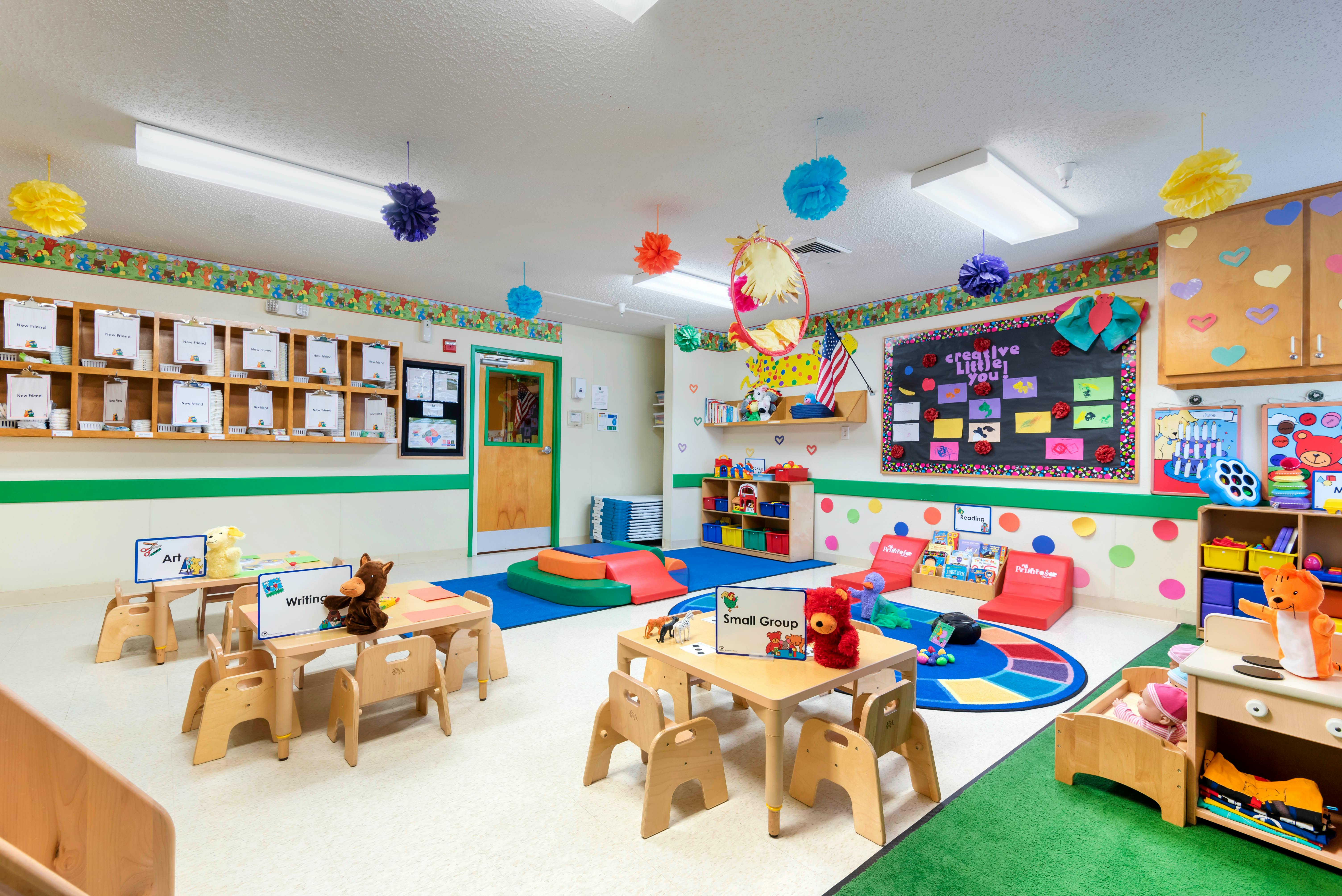 A colorful empty classroom with small tables and chairs, toys, and learning areas