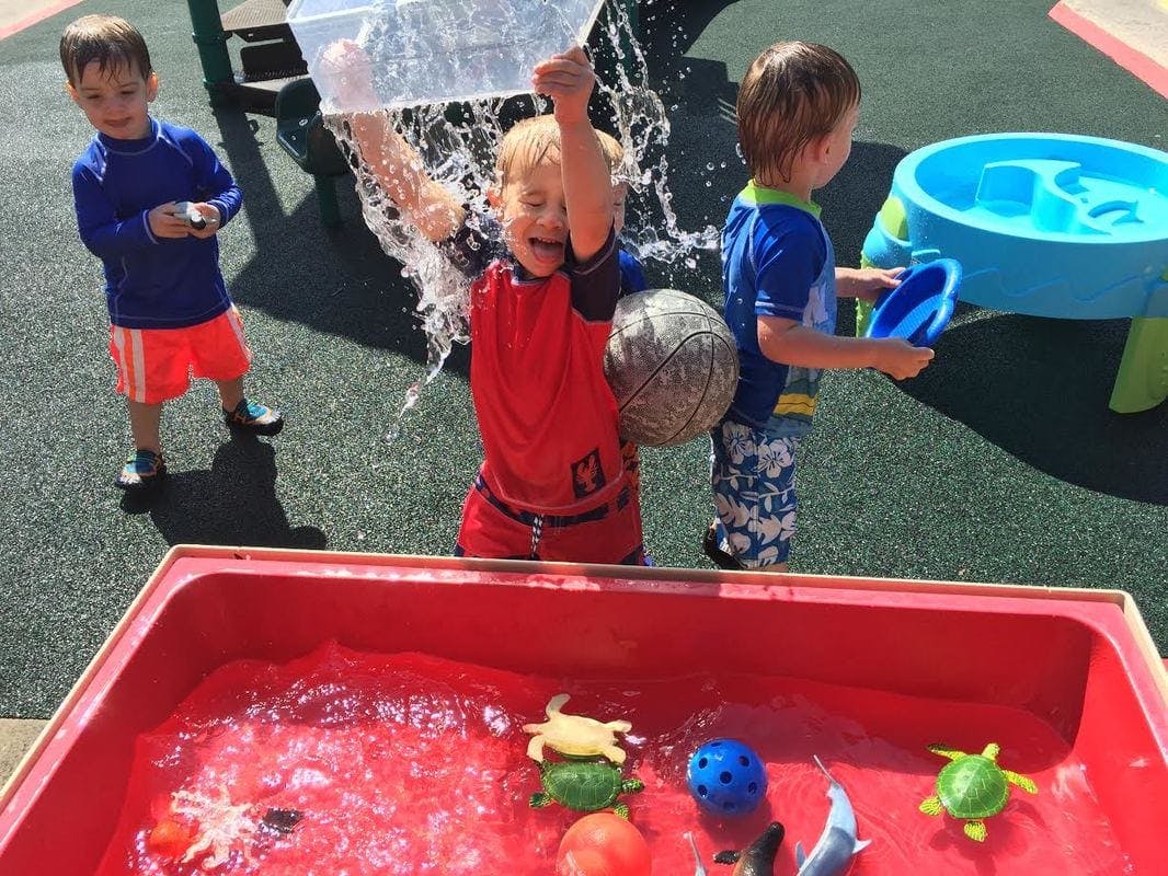 Child pouring water over their head from a container