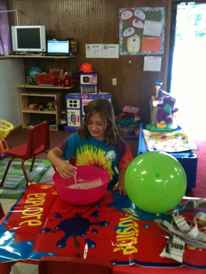Child mixing in a pink bowl on a red table