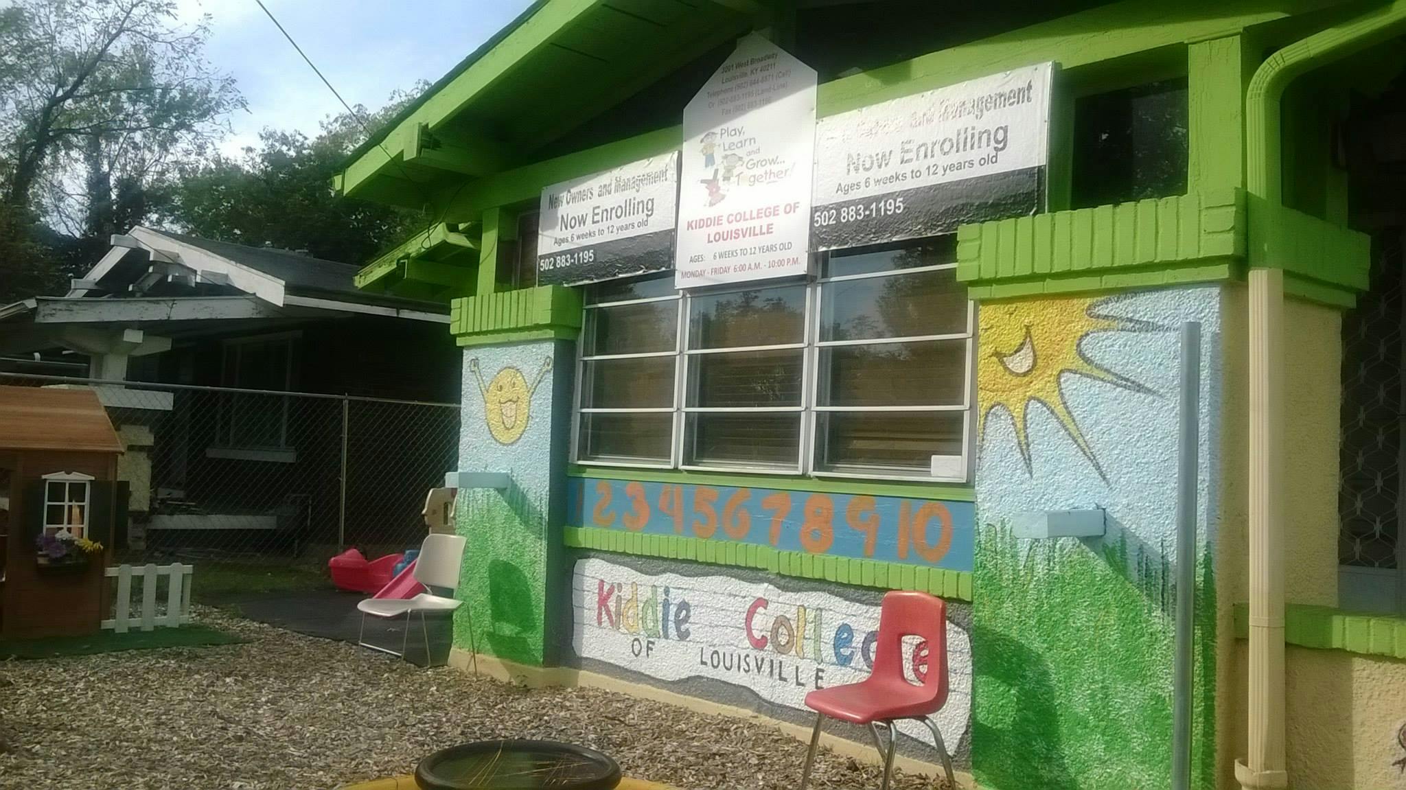 Green building with windows and a mural of a sun and grass