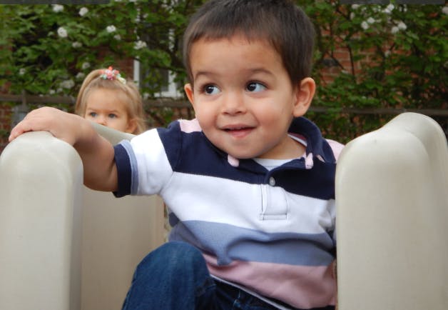 Child on a slide with another child in the background