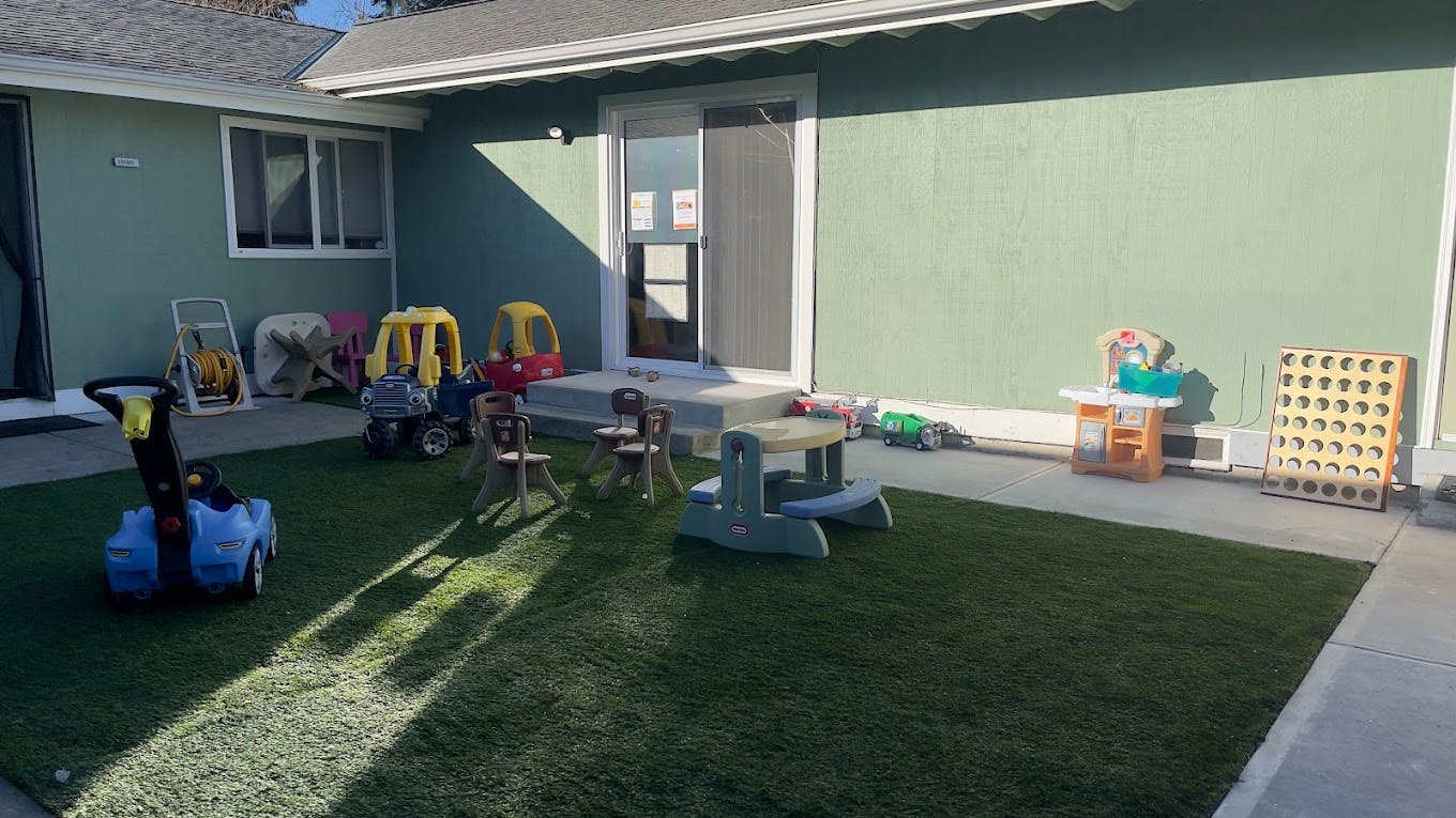 Outdoor play area with artificial grass and various child toys