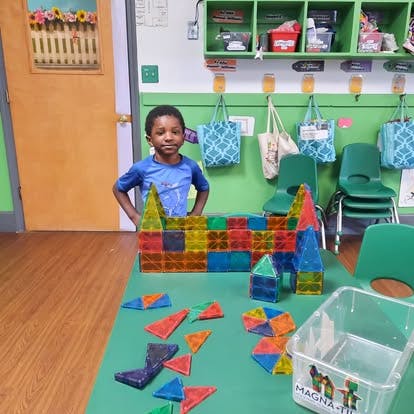 Child standing behind a table with colorful magnetic building blocks