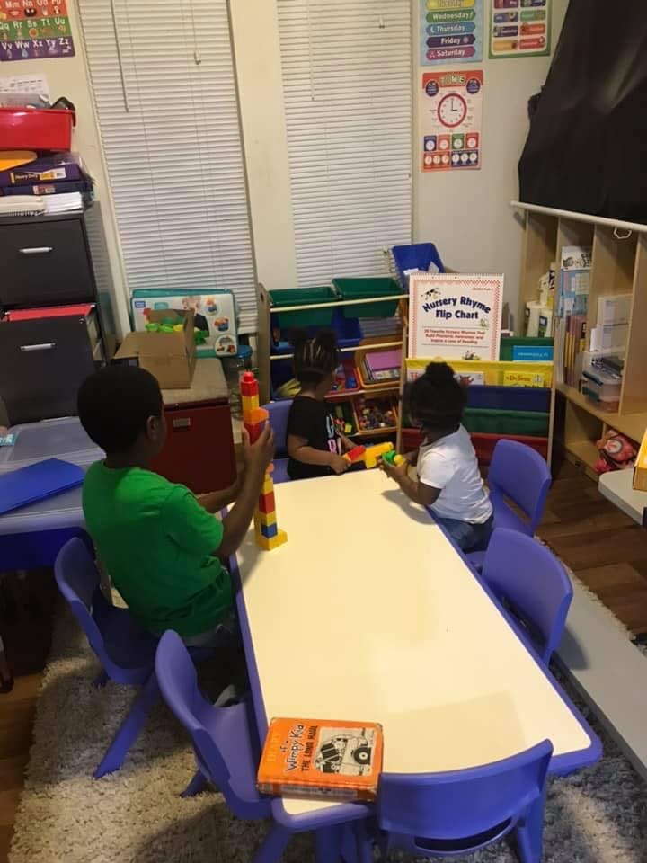 Three children playing with toys at a table in a classroom