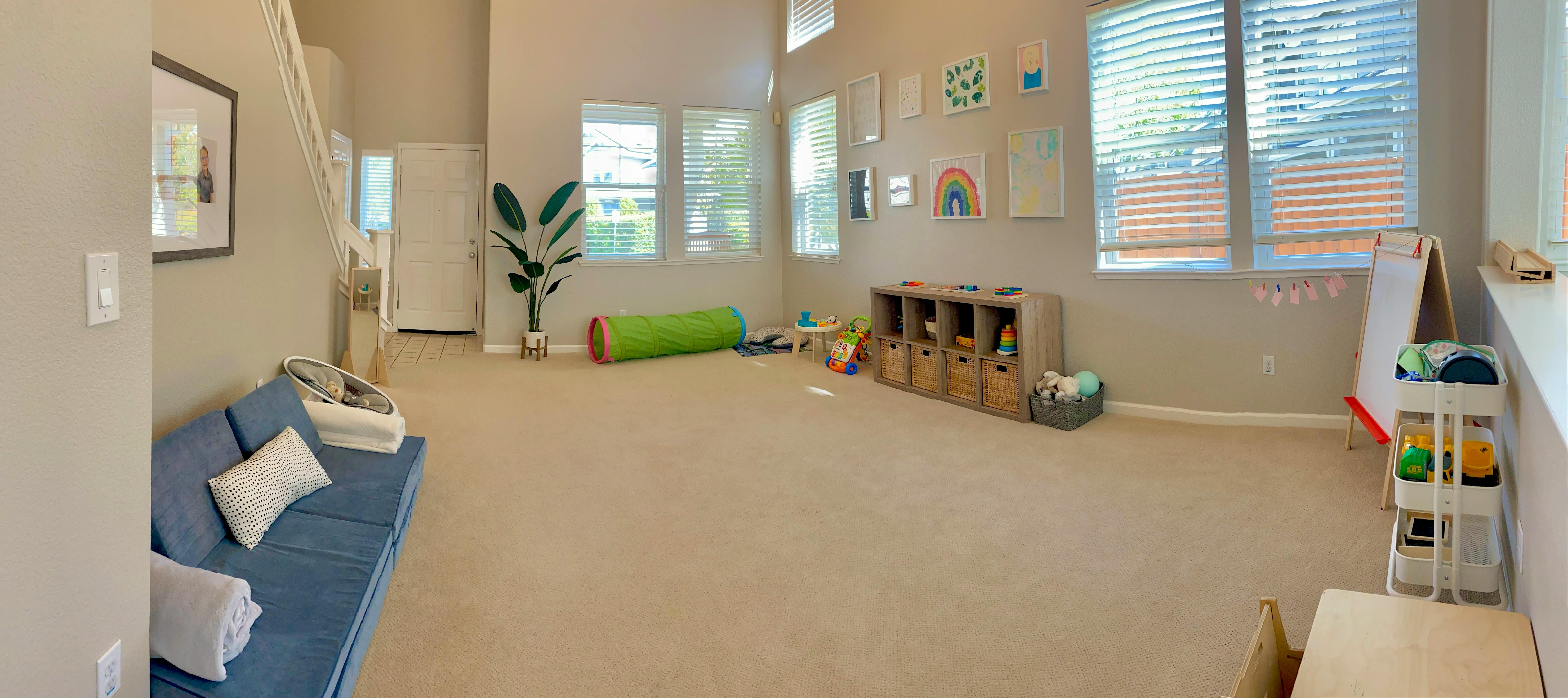 Children's play area with a blue floor couch, green play tunnel, and toy storage