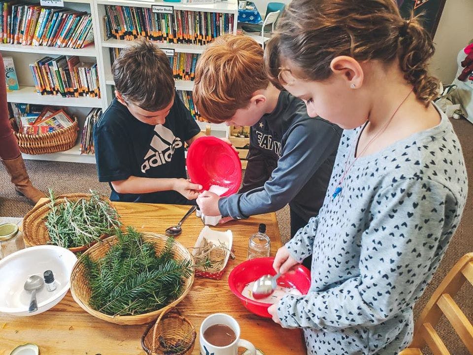 Three children mixing ingredients in bowls at a table
