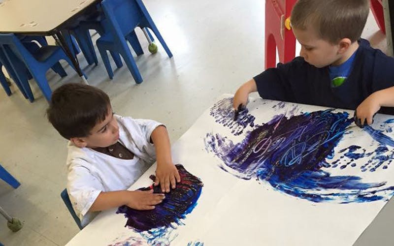 Two children finger painting in a classroom