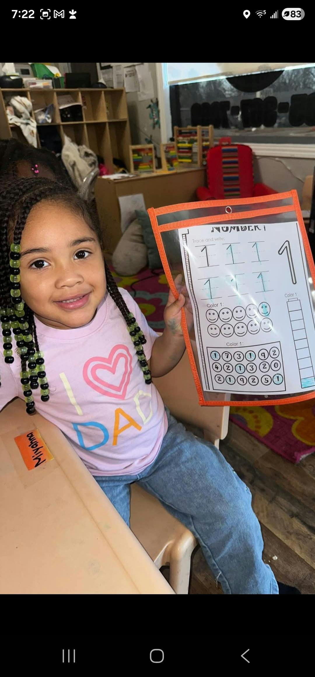 Child smiling while holding up a worksheet with numbers