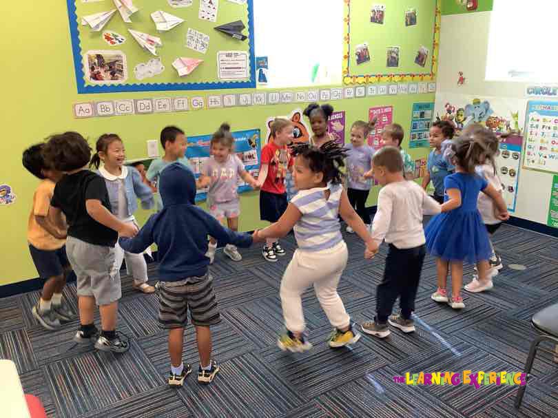 Children holding hands in a circle in a classroom