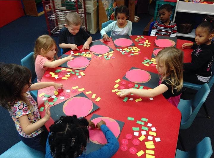 Children at a table doing an art activity with paper shapes