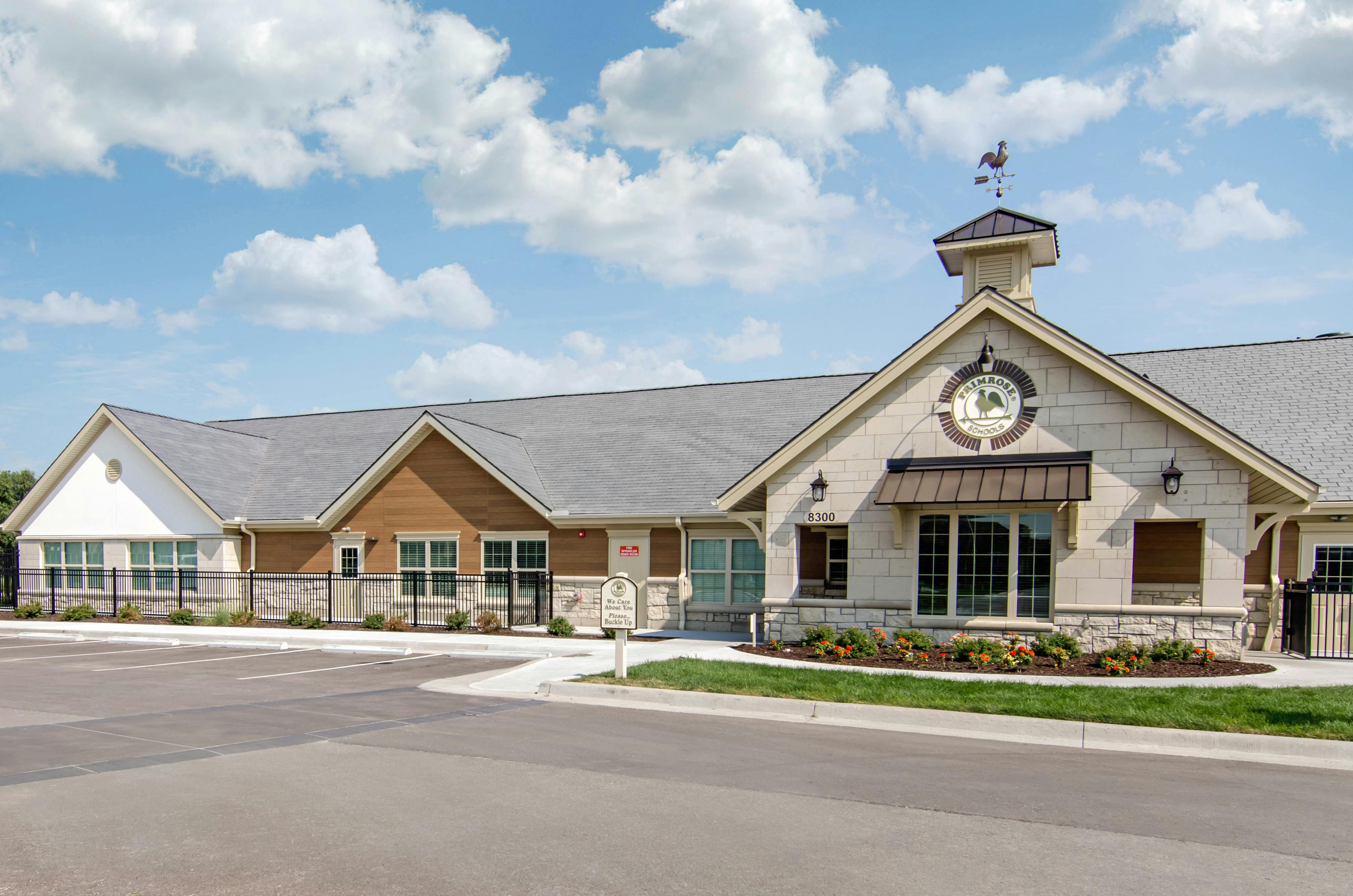 A beige building with a gray roof and a weathervane