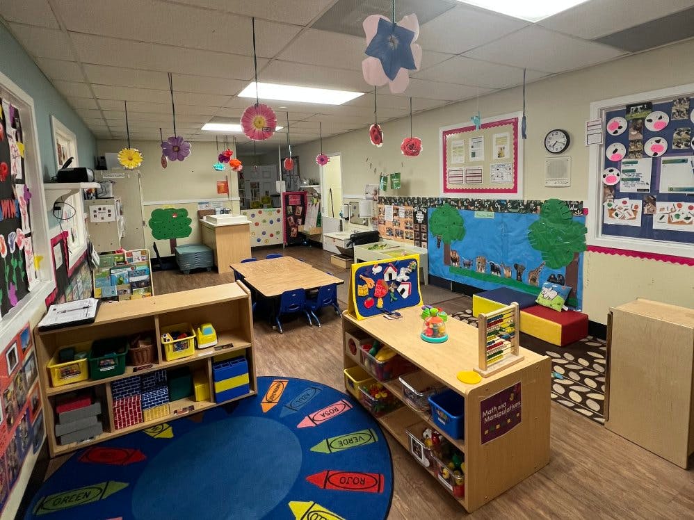 A colorful empty classroom with toys, tables, chairs, and decorations