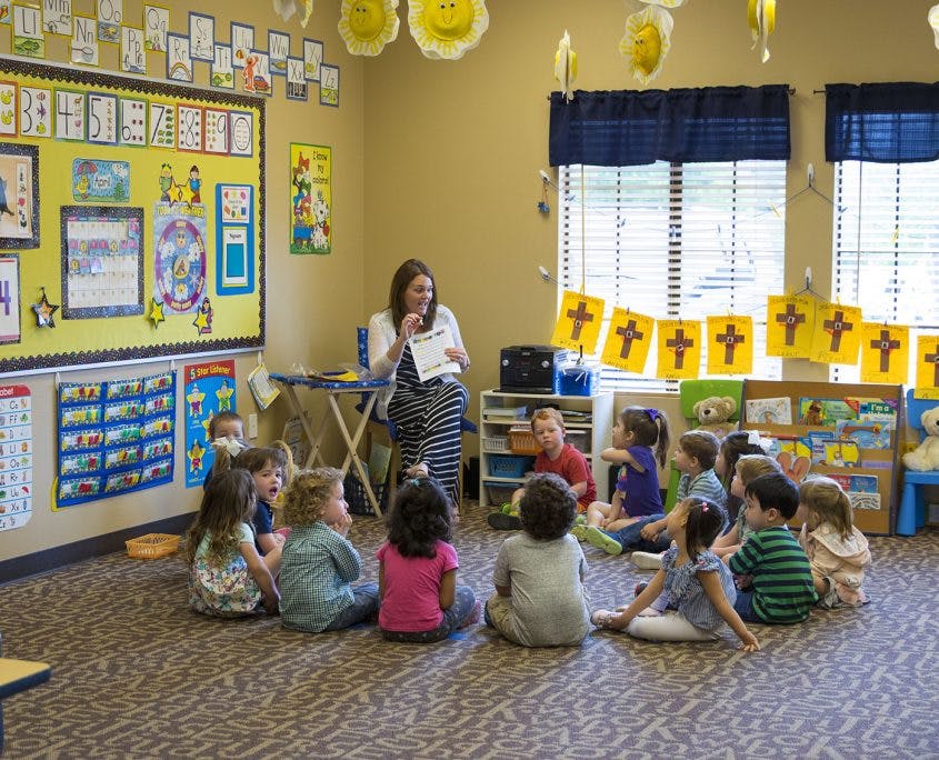 Adult person reading to children sitting on the floor in a classroom