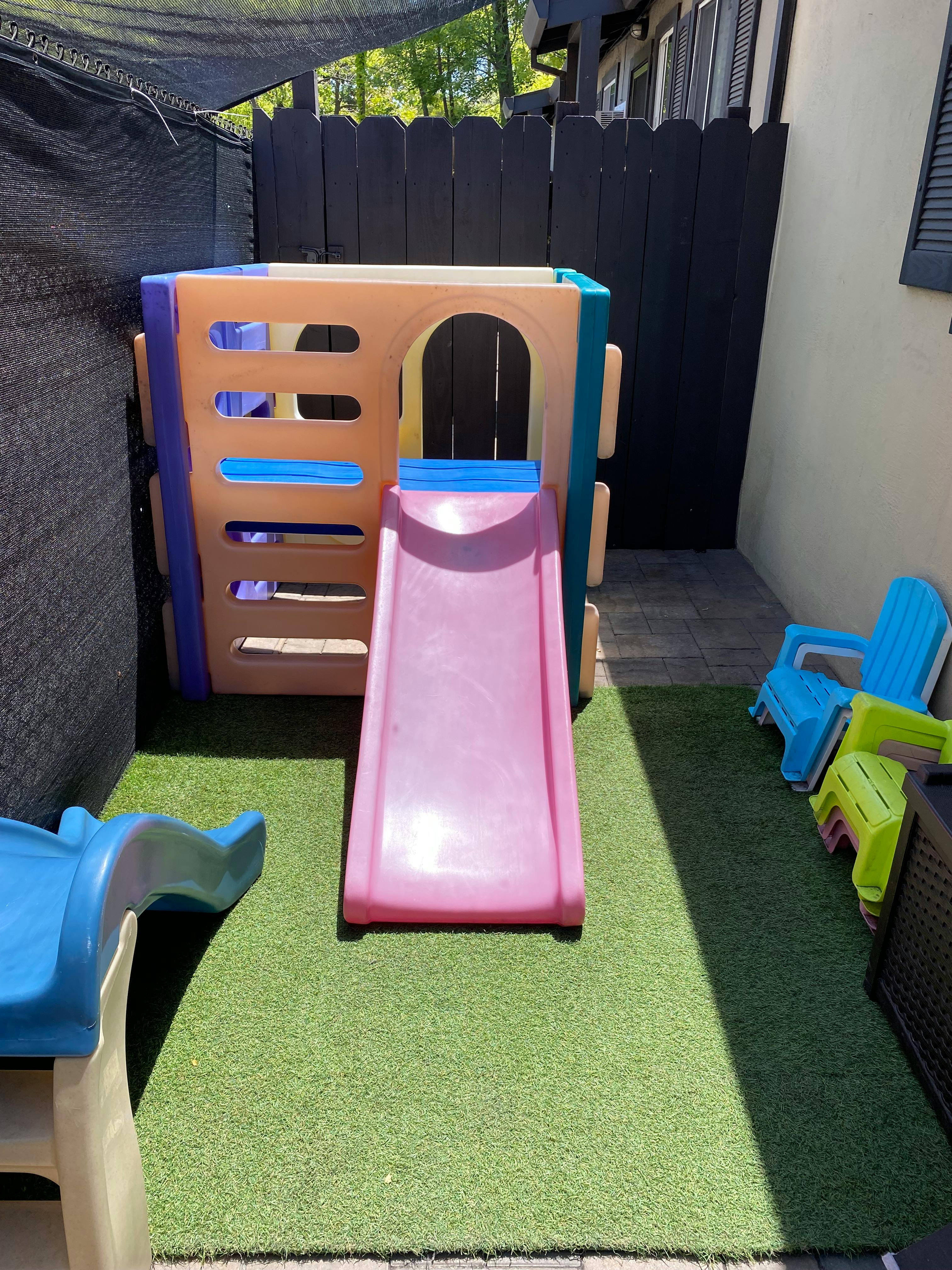 Play structure with a pink slide on artificial turf