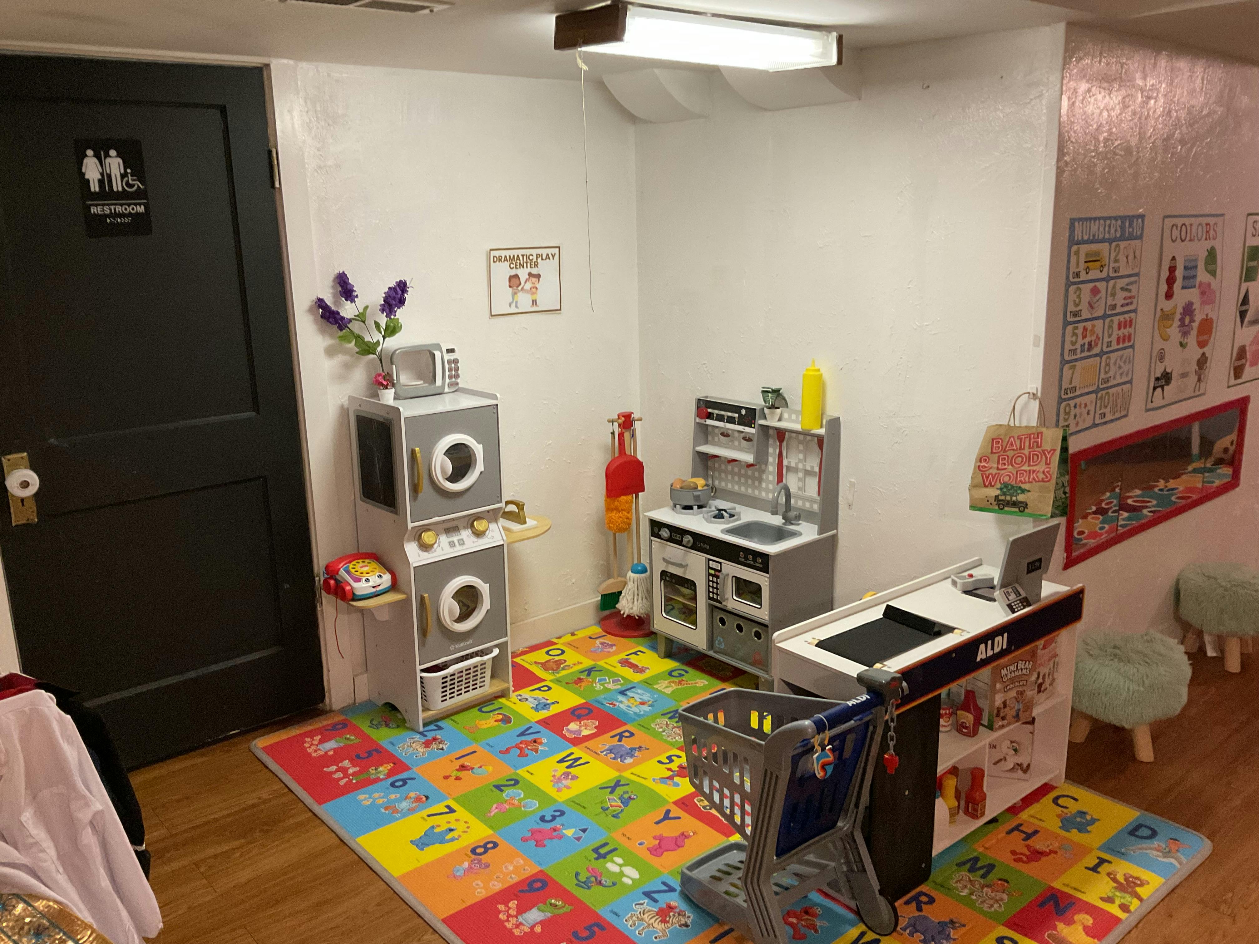 Play kitchen and shopping cart area on an alphabet floor mat