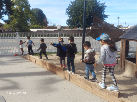 Children playing on a wooden beam